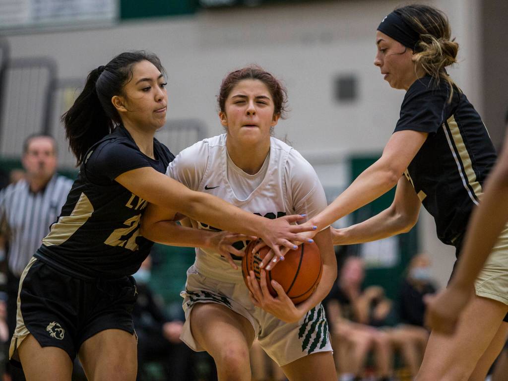Jacksons Arielle Leavens is double-teamed by two Lynnwood players as she drives to the hoop during the game on Tuesday in Everett. (Olivia Vanni / The Herald)