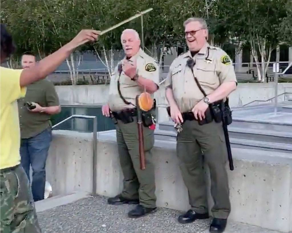 Benjamin Hansen dangles a doughnut in front of two law enforcement officers in Everett in July 2020. (Screen grab from video courtesy of Bennett Haselton)
