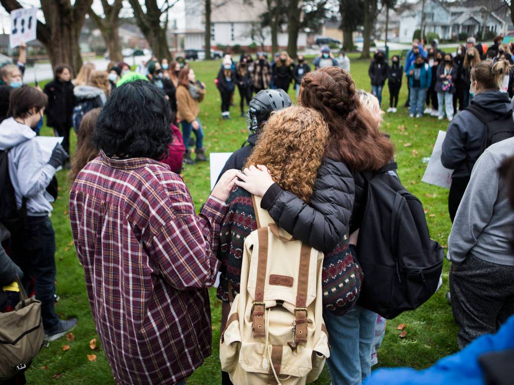 Students comfort each other while they listen to their peers share stories and demand systemic change from Everett School District on Dec. 16. (Olivia Vanni / The Herald)