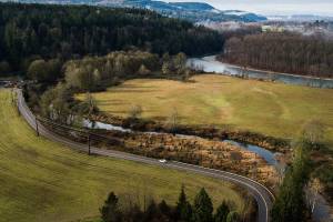 A car drives along a section of Ben Howard road that Snohomish County will raise due to flooding on Friday, Dec. 17, 2021 in Monroe, Wa. (Olivia Vanni / The Herald)