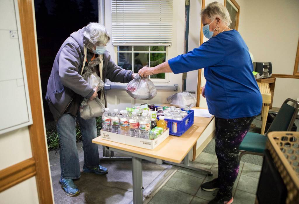 Roxana Boroujerdi hands out a to-go meal during Faith Lutheran Churchs hot meal night Nov. 30 in Everett. (Olivia Vanni / The Herald)