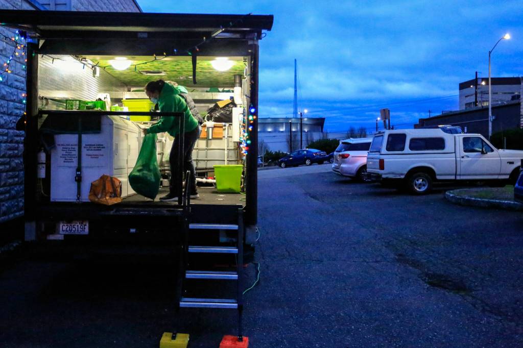 Yma Lopez gathers clothes to launder Dec. 1 at First Presbyterian Church in Everett. (Kevin Clark / The Herald)