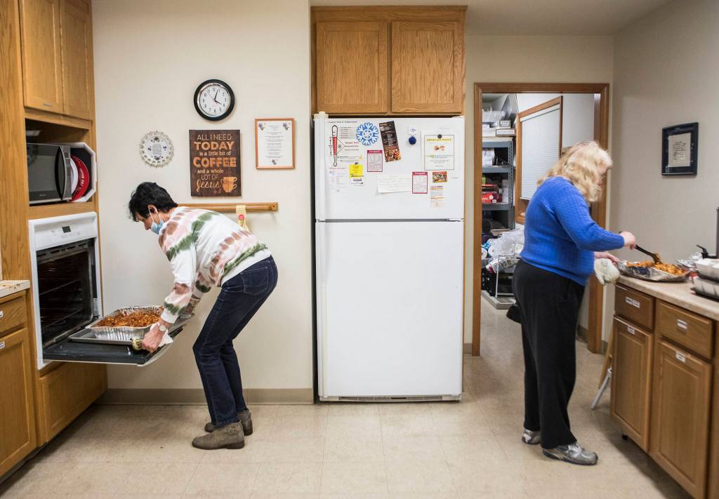 Barbara Schornak (left) and Holly Sullivan (right) heat food for Faith Lutheran Churchs hot meal night Nov. 30 in Everett. (Olivia Vanni / The Herald)