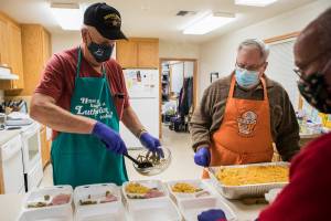 Mike Larson, left, puts together to-go meals with the help of Paul Rode, center, and Roger Chester, right, during Faith Lutheran Church's hot meal night on Tuesday, Nov. 30, 2021 in Everett, Wa. (Olivia Vanni / The Herald)