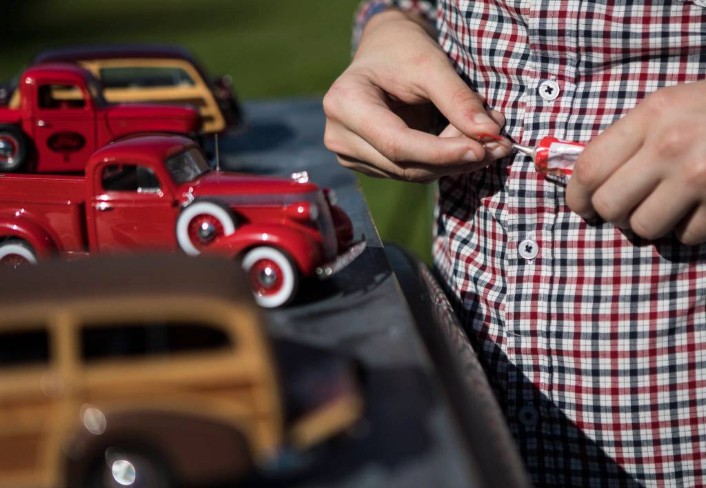 Anthony Schmidt does a quick repair of a rearview mirror that fell off one of his model cars during a photoshoot in front of Everett High School. (Olivia Vanni / The Herald)
