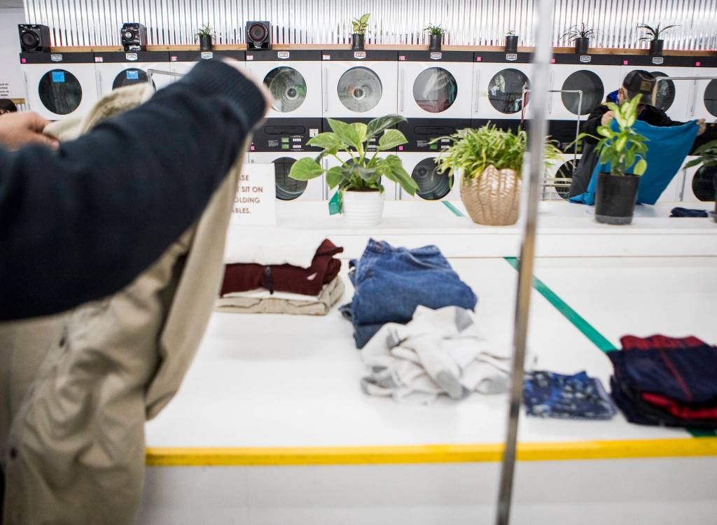 People fold their laundry during North Snohomish County Laundry Outreach on Dec. 1 in Arlington. (Olivia Vanni / The Herald)