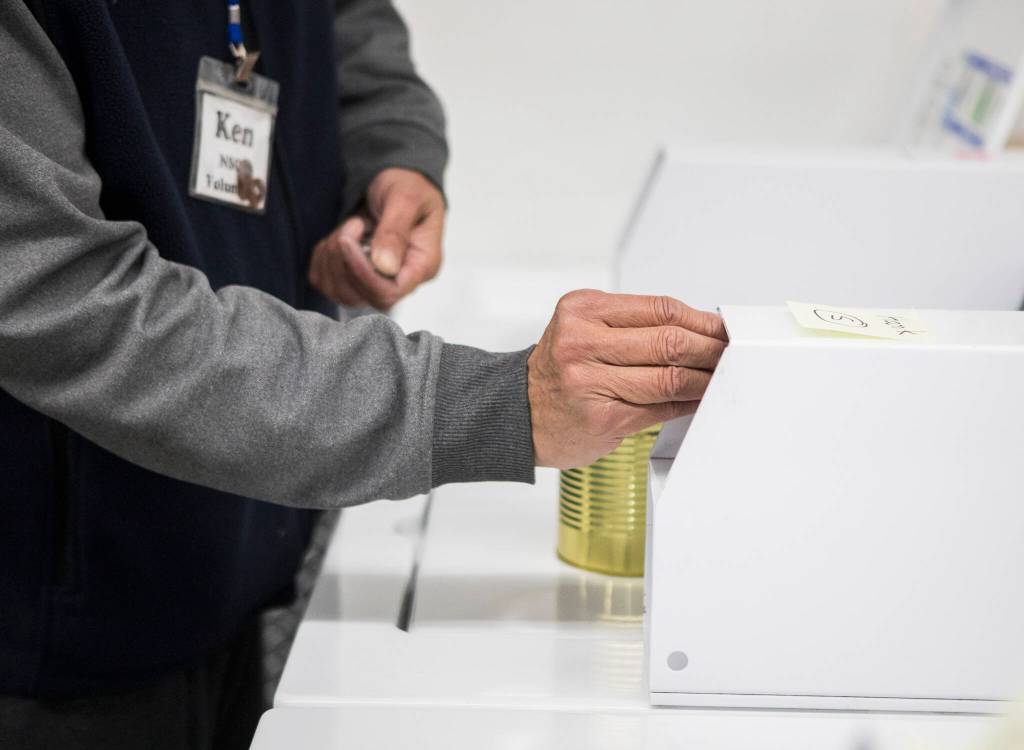 A volunteer places quarters in a washing machine during North Snohomish County Laundry Outreach on Dec. 1 in Arlington. (Olivia Vanni / The Herald)
