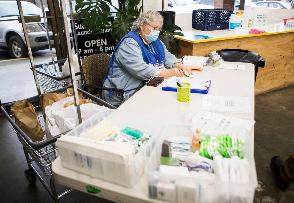 Grama Patty gives out a sticky note to mark a washing machine that is in use during North Snohomish County Laundry Outreach on Dec. 1 in Arlington. (Olivia Vanni / The Herald)