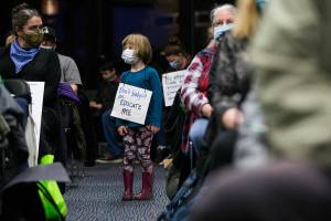 Juniper Player, 4, a student at the Early Learning Center, wears a sign in protest of the proposed plan to close pre-kindergarten facility on Tuesday, Nov. 30, 2021 in Everett, Wa. (Olivia Vanni / The Herald)