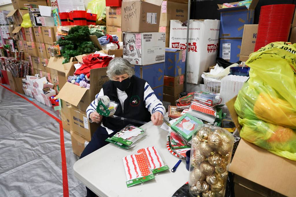 Volunteer Cathy Swain tapes gifts together at the Everett Boys Girls Club Christmas House on Monday. (Andy Bronson / The Herald)