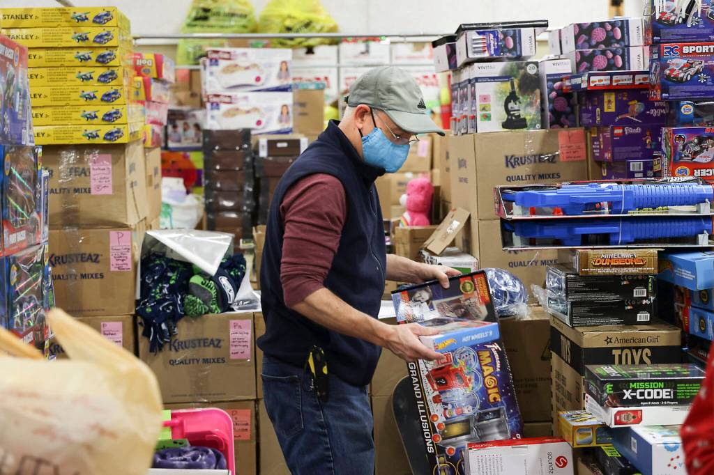 Volunteer Jim McFarland organizes gifts at the Everett Boys Girls Club Christmas House on Monday. (Andy Bronson / The Herald)