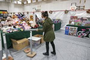 Teresa Ramadan uses a pylon as a hammer to build another as she and other volunteers tape, package and organize gifts as they get the Christmas House set up at Everett Boys & Girls Club on Monday, Nov. 29, 2021 in Everett, Washington.  (Andy Bronson / The Herald)