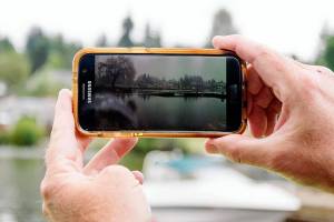 Lake Stevens resident Rick Trout shows a Feb. 2020 photo of the rising lake level in front of his home after a storm. (Isabella Breda / The Herald)