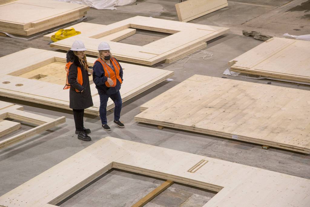 Foretrras Jenae Poe (left) and Cheri Marusa look over panels for a modular home made from cross-laminated timber inside a warehouse on Marine View Drive in Everett. (Andy Bronson / The Herald)