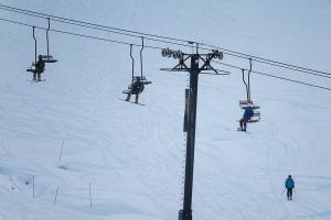 People ride one person to a double chair lift on opening day at Steven's Pass on Friday, Dec. 4, 2020 in Skykomish, Wa. (Olivia Vanni / The Herald)