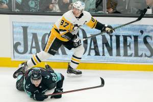 Seattle Kraken defenseman Carson Soucy (28) goes down as Pittsburgh Penguins center Sidney Crosby watches the puck during the second period of an NHL hockey game, Monday, Dec. 6, 2021, in Seattle. (AP Photo/Ted S. Warren)