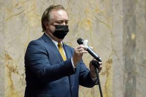 Sen. Doug Ericksen, R-Ferndale, wipes off a microphone before speaking on the Senate floor Monday, Jan. 11, 2021, at the Capitol in Olympia, Wash. Washington state's Legislature convened Monday under a large security presence because of concerns about efforts by armed groups who might try to disrupt the proceedings or occupy the Capitol, which is closed to the public due to the ongoing pandemic. (AP Photo/Ted S. Warren)