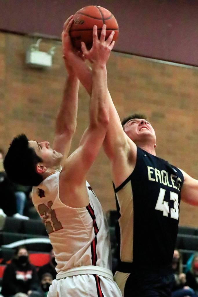 Mountlake Terraces Vito Mkrtychyan, left, and Arlingtons Ethan Martin jumps for a rebound Friday evening at Mountlake Terrace High School on December 10, 2021. The Eagles won 70-55. (Kevin Clark / The Herald)
