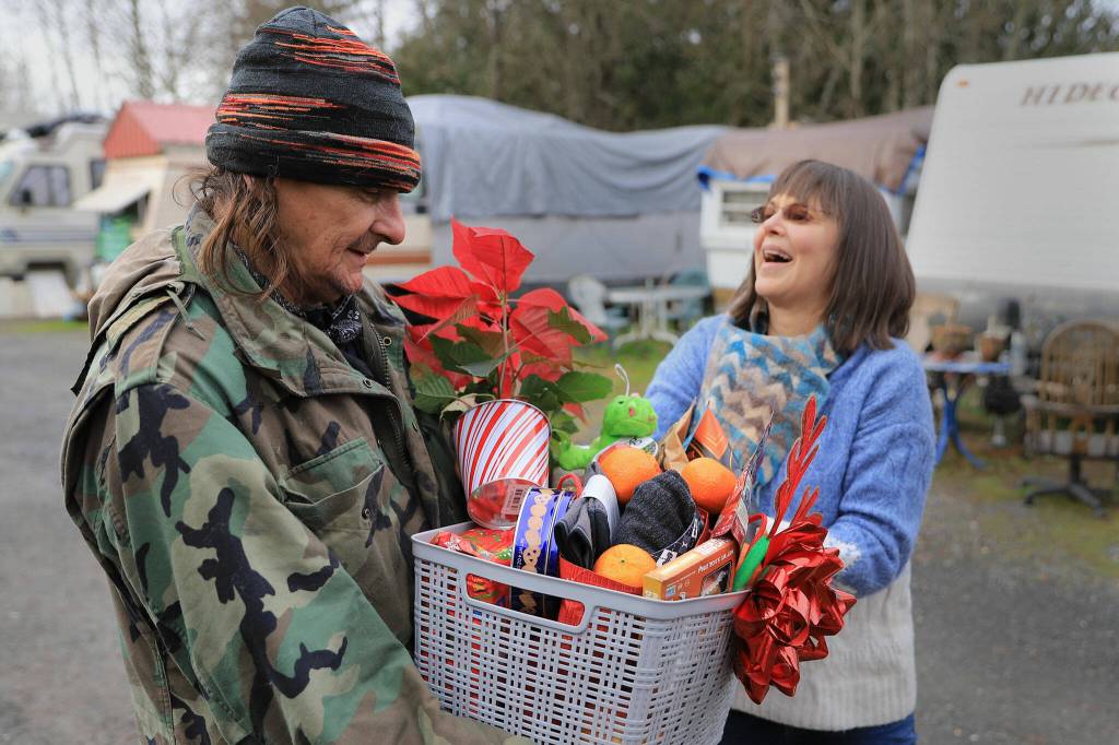 Tony Coty receives a gift basket from Penelope Protheroe Friday in Granite Falls on Dec. 17. (Kevin Clark / The Herald)