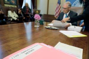 Washington Gov. Jay Inslee uses a red pen to veto sections of the state capital budget, Tuesday, May 21, 2019, at the Capitol in Olympia, Wash. Inslee signed the state's capital, operating, and transportation budgets Tuesday, officially designating funds — and new taxes — to pay for state programs for the next two years. (AP Photo/Ted S. Warren)