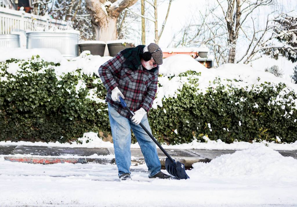 Tim Knopf shovels out a parking spot from his family coming to visit Monday in Everett. (Olivia Vanni / The Herald)