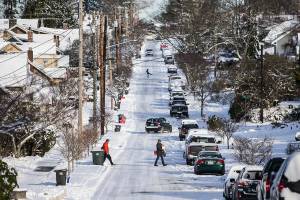 Cars and pedestrians carefully navigate the ice and snow along Grand Avenue on Monday, Dec. 27, 2021 in Everett, Wa. (Olivia Vanni / The Herald)