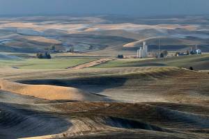 A grain elevator and the rolling hills of the Palouse farmland are shown from the top of Steptoe Butte near Colfax, Wash., on Oct. 28, 2019. The Moscow-Pullman Daily News reported Tuesday, Dec. 21, 2021 that the largest remaining area of native Palouse prairie in southeastern Washington state will be preserved thanks to a recent transaction that moved hundreds of acres of the butte into public ownership by the Washington Department of Natural Resources. The top of the butte is a Washington State park but much of its flanks were in private ownership. (AP Photo/Ted S. Warren)