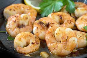 prawns shrimps roasted in a black pan with garlic, lemon, spices  and italian parsley garnish, close up, selected focus, narrow depth of field