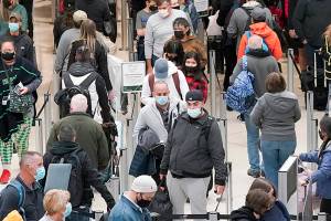 FILE - Travelers wear masks as they wait in a line for a TSA security check, Dec. 10, 2021, at Seattle-Tacoma International Airport in Seattle. President Joe Biden on Monday, Dec. 13, 2021, will sign an executive order aimed at saving Americans time and frustration when seeking a broad array of federal services, like renewing passports, applying for Social Security benefits and getting aid after natural disasters. (AP Photo/Ted S. Warren, File)