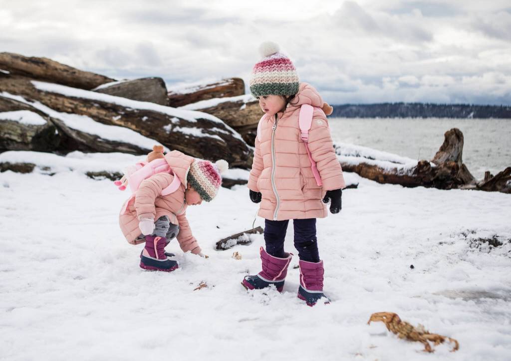 Twins Ella Rose Pogorely and Anna Grace Pogorely, 2, inspect the snow at Lighthouse Park on Thursday in Everett. (Olivia Vanni / The Herald)