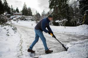 Tim Pfahl finishes shoveling his long driveway for the third time this week on Thursday, Dec. 30, 2021 in Everett, Wa. (Olivia Vanni / The Herald)