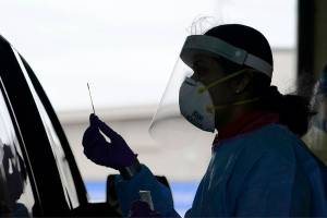 FILE - In this Oct. 23, 2020, file photo, University of Washington research coordinator Rhoshni Prabhu holds up a swab after testing a passenger at a free COVID testing site in Seattle. Deaths per day from the coronavirus in the U.S. are on the rise again, just as health experts had feared, and cases are climbing in nearly every single state. (AP Photo/Elaine Thompson)