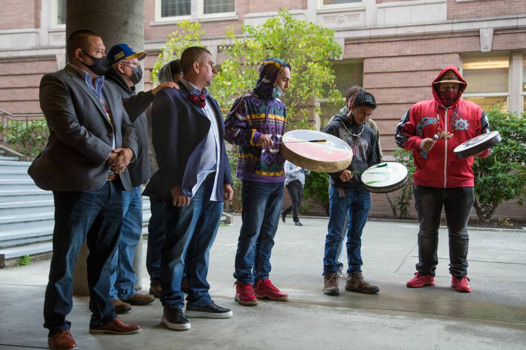 Hazen Shopbell (left) and Anthony Paul (third from left) listen to a drum circle play before a hearing at Skagit County Superior Court on Oct. 25 in Mount Vernon. (Andy Bronson / The Herald)