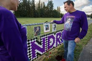 Chad Hofland and his wife Xochitl look at a photograph of their son Andre, 17, at a memorial set up along 116th Street on Thursday, Oct. 7, 2021 in Marysville, Wa. Andre was was shot and killed in robbery on January 5th, 2021. (Olivia Vanni / The Herald)