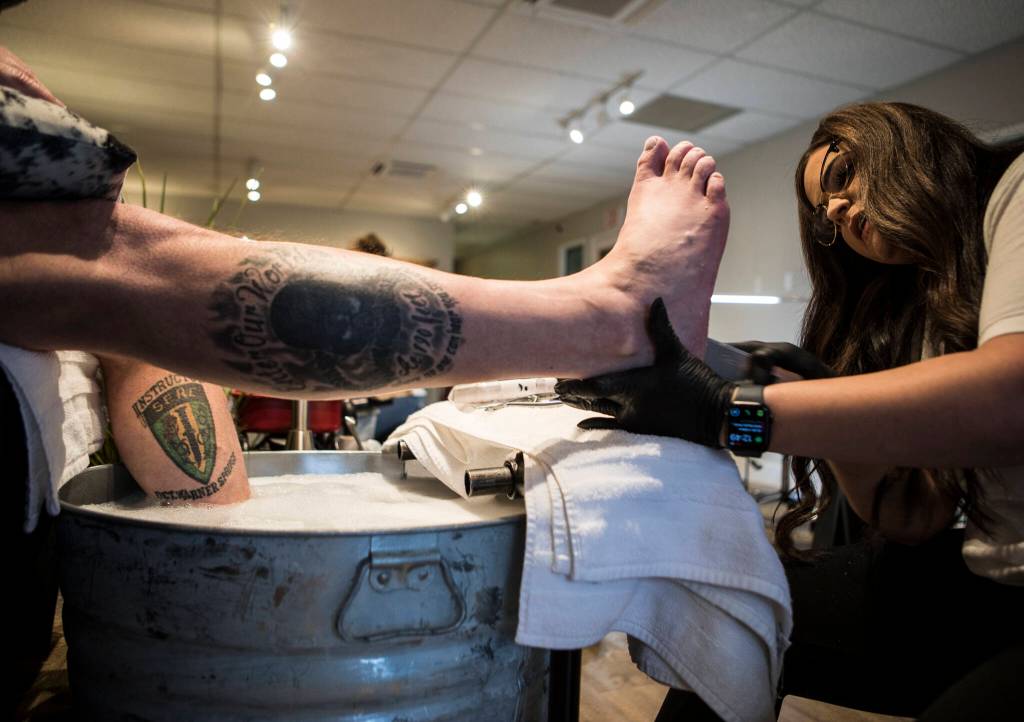 Laura Finsen, owner of Nail Flare in Stanwood, works on Keith Reyes feet. (Olivia Vanni / The Herald)