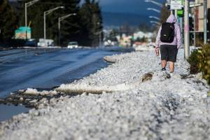 A pedestrian navigates a slush filled sidewalk along Rucker Avenue on Monday, Jan. 3, 2022 in Everett, Wa. (Olivia Vanni / The Herald)