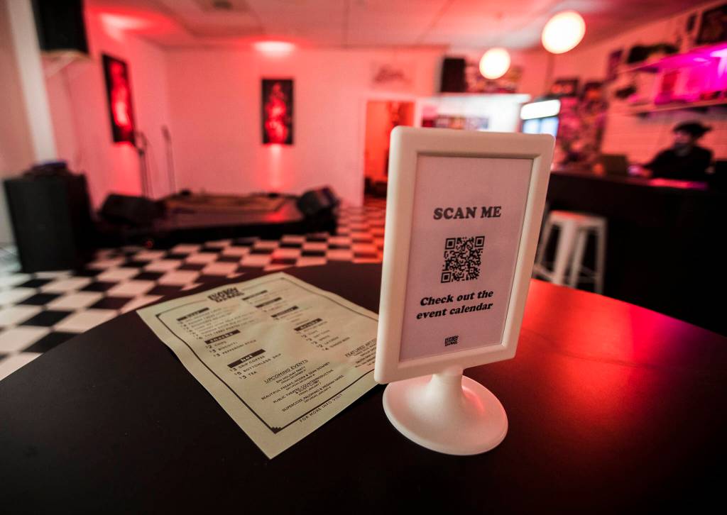 A bar menu and poster with the Lucky Dimes event calendar sit on a bar table at the empty establishment in Everett. (Olivia Vanni / The Herald)