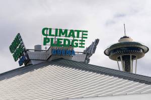The roof-top sign for Climate Pledge Arena is shown next to the Space Needle, Wednesday, Oct. 20, 2021, ahead of the NHL hockey Seattle Kraken's home opener Saturday against the Vancouver Canucks in Seattle. The historic angled roof of the former KeyArena was preserved, but everything else inside the venue, which will also host concerts and be the home of the WNBA Seattle Storm basketball team, is brand new. (AP Photo/Ted S. Warren)