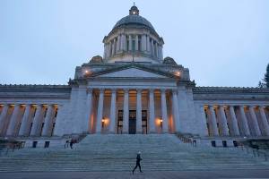 FILE - A jogger runs past the Legislative Building just before dusk on Dec. 21, 2021, at the Capitol in Olympia, Wash. Flush with cash, Washington state lawmakers return to Olympia on Monday, Jan. 10, 2022, with Democrats and Republicans disagreeing over how to spend the unexpected windfall. (AP Photo/Ted S. Warren, File)