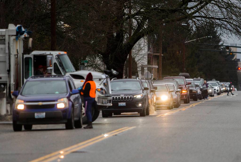 People get out of their cars along Wetmore Avenue to see how far they are from a testing site Thursday in Everett. (Olivia Vanni / The Herald)