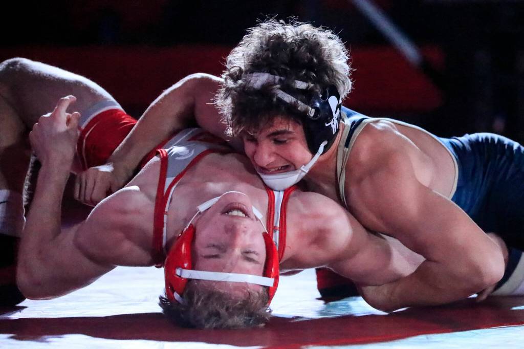 Arlingtons Dustin Baxter works to pin Stanwoods Cameron ONeill in the 145-pound weight class at Stanwood High School on Thursday evening. (Kevin Clark / The Herald)