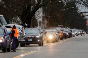 People get out of their cars along Wetmore Avenue to check how much farther until the testing site on Thursday, Jan. 6, 2022 in Everett, Washington. (Olivia Vanni / The Herald)
