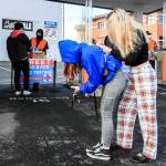 Sam Dawson (right) fills out a registration card with the help of her friend, Shay Daniels, on Thursday at the walk-up COVID testing center on Wetmore Avenue in Everett. (Kevin Clark / The Herald)