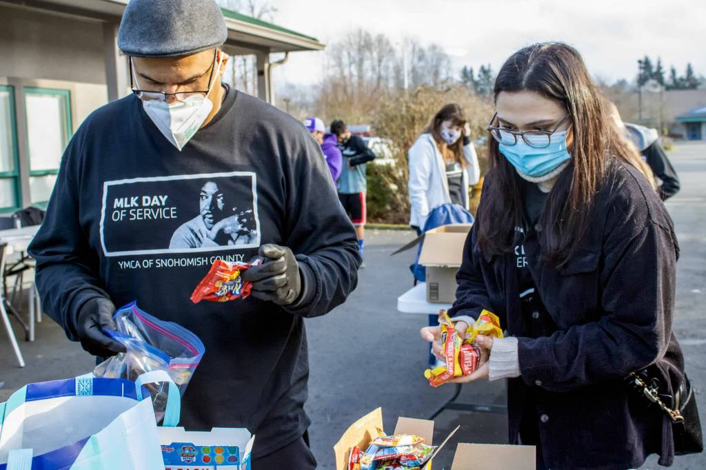 JJ Frank, executive director of the Marysville YMCA, and Mariel Gonzalez, administrative social worker for LINC NW, fill care packages during the Marysville MLK Day of Service on Monday. (Isabella Breda / The Herald)
