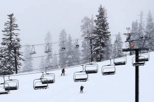 Skiers make their way uphill under idle lift chairs at the Summit at Snoqualmie Ski Area as fresh snow falls, Wednesday, Feb. 14, 2018, in Snoqualmie Pass, Wash. Several inches of snow fell Wednesday, and the area shown was scheduled to open to skiers and begin lift operation later in the day. (AP Photo/Ted S. Warren)