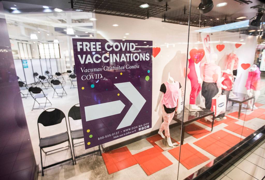 Signs direct people to the entrance of the new free COVID-19 vaccination site at the Everett Mall. (Olivia Vanni / The Herald)