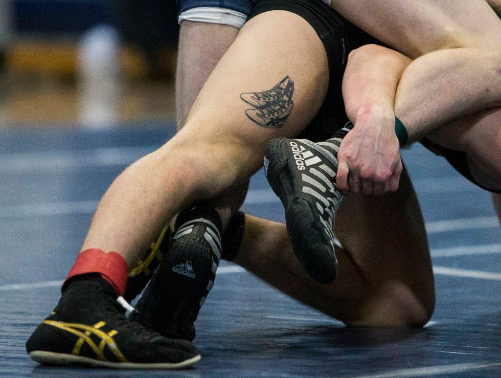 A tattoo of wrestling shoes is visible on Lake Stevens Tyler Flouts leg during a wrestling meet on Tuesday in Snohomish. (Olivia Vanni / The Herald)