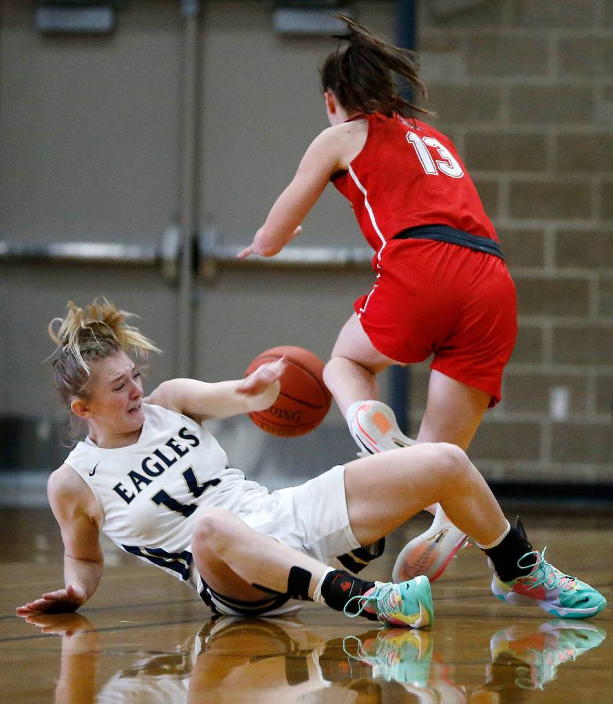 Arlingtons Keira Marsh and Snohomishs Ella Gallatin chase after a loose ball during a game Monday at Arlington High School. (Ryan Berry / The Herald)