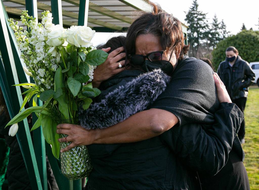 Mourners hug at the conclusion of the funeral for Adriana and Mariel Gil Friday, Jan. 28, 2022, at Cypress Lawn Memorial Park in Everett. (Ryan Berry / The Herald)