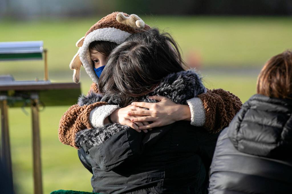 Addisun Martin-Row hugs Betsy Alvarado during the funeral for Alvarados children, Adriana and Mariel Gil, Friday, Jan. 28, 2022, at Cypress Lawn Memorial Park in Everett. (Ryan Berry / The Herald)